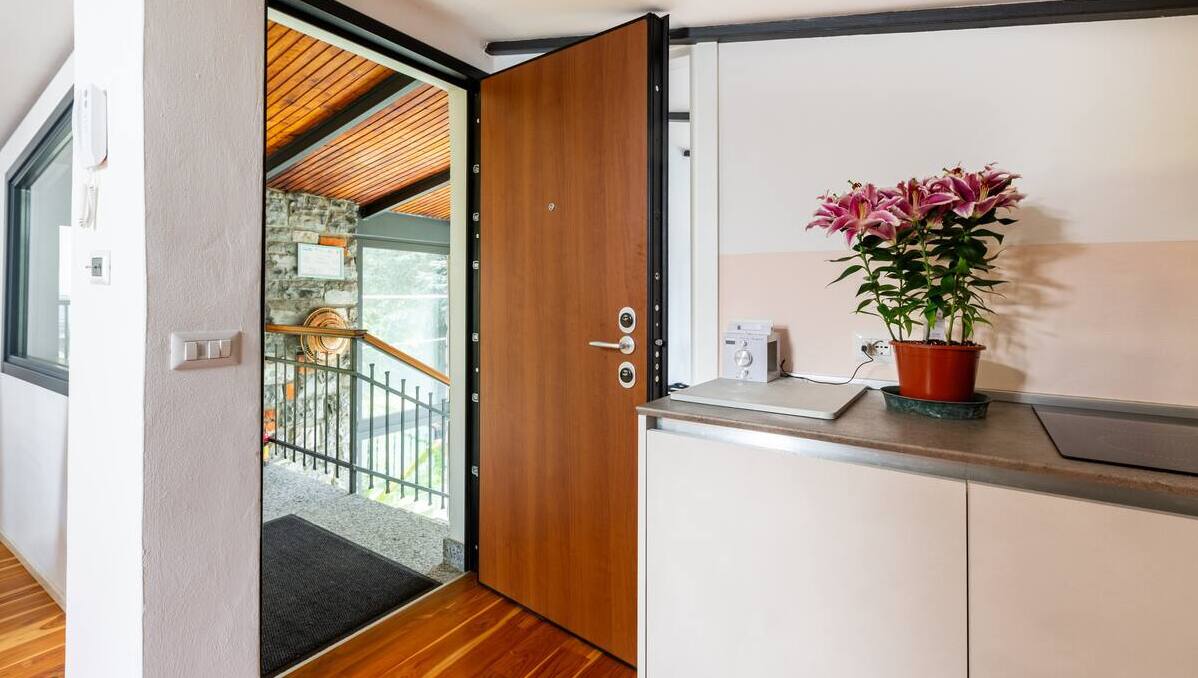 Ingresso accogliente de La Casa degli Ulivi con porta di sicurezza in legno, pavimento in parquet e dettagli eleganti come fiori freschi - Accesso indipendente con vista sul giardino